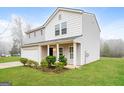 Inviting two-story home with a covered porch, lush green lawn, and convenient two-car garage at 415 Arthurs Ln, Covington, GA 30016
