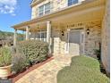 Inviting front porch features brick columns, stone floors, and a charming front door entrance at 115 Woodcanoe Ct, Peachtree City, GA 30269