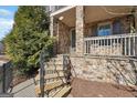 Inviting covered front porch with stone pillars and railing, steps, and black wrought iron railing at 1685 Tabor Dr, Marietta, GA 30062