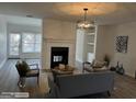 Bright living room showcasing fireplace, modern chandelier, neutral colors and wood-look flooring at 8053 Woodlake Dr, Riverdale, GA 30274