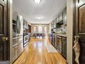 Modern kitchen with stainless steel appliances, granite countertops, dark wood cabinets, and an adjacent dining area with hardwood floors at 230 Mapledale Trl, Sharpsburg, GA 30277