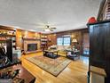 Cozy living room with wood-paneled walls, a brick fireplace, built-in bookshelves, and hardwood floors with an area rug at 230 Mapledale Trl, Sharpsburg, GA 30277
