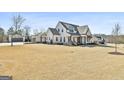 Expansive front yard showcases a modern farmhouse with a three-car garage and basketball hoop on a sunny day at 132 Platinum Rdg, Sharpsburg, GA 30277
