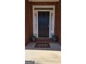 Inviting front door with sidelights, potted plants, and a 'Welcome' mat, set in a classic brick facade at 35 Abelia Dr, Covington, GA 30014