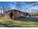 Single-story brick house with a carport, surrounded by trees and green space at 7427 Hollis Rd, Douglasville, GA 30135
