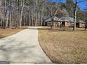 Long concrete driveway leading to a brick house, surrounded by mature trees and landscaping at 170 Royal Ridge Way, Fayetteville, GA 30215