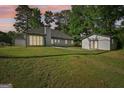 Rear exterior view of home with an outbuilding, lush lawn, and abundant natural light from large windows at 2768 Southpark Sw Blvd, Conyers, GA 30094