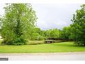 Scenic view of a large, green yard with mature trees and a small pond with a wooden pier at 956 Shadowford Fls, Lithonia, GA 30058