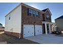 Side view of a charming two-story brick home featuring a two-car garage and white siding on one side at 1224 Hibiscus Way, Mcdonough, GA 30253