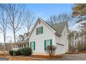 Side view of a two-story house showing the green shutters, green roof, two-car garage and well maintained landscape at 495 N Oakland Cir, Mcdonough, GA 30253