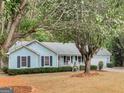 Single-story light blue home featuring a welcoming front porch and tree-lined yard at 220 Melrose Way, Mcdonough, GA 30252