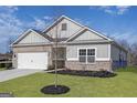 Charming single-story home boasts a two-car garage, manicured lawn, and brick and siding accents at 3201 Azteca Way, Dacula, GA 30019