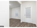 Bright entryway featuring wood floors, a white door with blinds, and a view into an adjacent room at 1048 Claas Way, Locust Grove, GA 30248