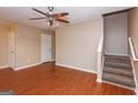 Inviting living area featuring wood floors, ceiling fan, access to stairs and a white door at 5797 Strathmoor Manor Cir, Lithonia, GA 30058