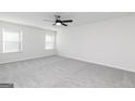 Bright bedroom featuring a ceiling fan, two windows for natural light, and cozy carpeting at 3200 Azteca Way, Dacula, GA 30019