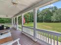 Covered porch with ceiling fan, white columns and railings, furniture, and an American flag at 2110 Mcgarity Rd, Mcdonough, GA 30252