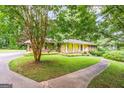 Inviting ranch home with a lush green lawn and mature trees, showcasing its tranquil setting and charming curb appeal at 437 Forrest Ave, Fayetteville, GA 30214