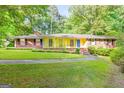 Charming ranch home with a bright yellow exterior, brick accents, blue door, and a well-manicured front lawn at 437 Forrest Ave, Fayetteville, GA 30214