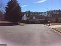 View of a quiet street with homes, mature trees and a wooden fence at 2054 Gwinn Dr, Norcross, GA 30071