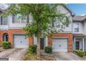 Charming townhouse featuring a brick facade, single-car garage, and a mature tree at 473 Tufton Se Trl, Atlanta, GA 30354