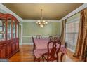 Formal dining room features elegant chandelier, complemented by hardwood floors and crown molding at 770 Huiet Dr, Mcdonough, GA 30252