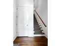 Hallway with hardwood floors, white door, and carpeted stairs with a wooden handrail at 9135 Selborne Ln, Chattahoochee Hills, GA 30268