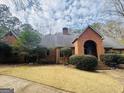 Attractive brick home boasts a well-maintained lawn, mature trees, and classic architectural detailing on a sunny day at 9255 Betony Wood Trl, Jonesboro, GA 30236