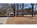 Serene exterior view of a home, nestled among trees, with a long driveway leading to the attached garage at 97 Arnold Rd, Hampton, GA 30228