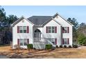 Two story home featuring classic white siding and red shutters with a lawn and mature trees at 231 Ashley Trace Dr, Locust Grove, GA 30248