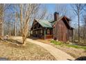 Log cabin exterior with a green roof, featuring a walkway and surrounding trees at 1225 Pitts Chapel E, Newborn, GA 30056
