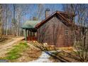 Side view of a log cabin with a covered porch and chimney, showcasing its rustic design at 1225 Pitts Chapel E, Newborn, GA 30056