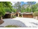 Stunning home exterior features a stone facade, mature trees, and a paved driveway, with great curb appeal at 4421 Paradise Cir, Vinings, GA 30339
