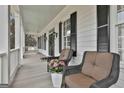 Relaxing front porch features wicker chairs, wood flooring, and views of the surrounding landscape at 605 St. Charles Pl, Fayetteville, GA 30215