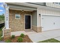 Close up of a front door with stone and siding exterior, a well manicured lawn, and a two car garage at 11192 Cornerstone Way, Hampton, GA 30228