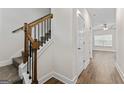 Hallway featuring wood flooring, white trim, and stairs with wood and black metal railings at 11192 Cornerstone Way, Hampton, GA 30228