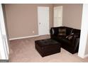 Comfortable living room with a dark leather sofa, ottoman, and neutral carpet at 4286 Rosehall Ct, South Fulton, GA 30349