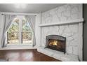 Inviting living room with a stone fireplace, hardwood floors, and a bright window at 4097 Cripple Creek Nw Dr, Kennesaw, GA 30144