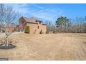 Exterior shot of home, showcasing a large lawn and wooded area beyond the manicured backyard at 124 Shelton Dr, Mcdonough, GA 30252
