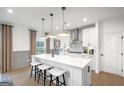 A modern kitchen with a white quartz island, counter seating, stainless steel appliances, and lots of natural light at 5711 Tillman Way, Powder Springs, GA 30127
