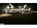 Night shot of a beautifully lit two-story home with stone accents and a large, manicured front lawn at 209 Wynnward Way, Sharpsburg, GA 30277