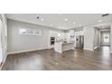 Open-concept kitchen and living area with wood floors, white cabinetry, stainless steel appliances, and natural light at 3390 Steinbeck St, Cumming, GA 30041