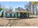 Inviting home with a covered front porch, featuring a classic design and mature trees on a sunny day at 1444 Norman Berry Dr, East Point, GA 30344