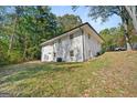 Rear exterior view of the white brick home on a lot with mature trees, showcasing its spacious backyard at 256 Butterworth Rd, Canton, GA 30114