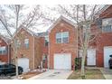 View of a brick townhome with a single car garage, well manicured lawn, and minimal winter foliage at 6517 Snowbird Ln, Douglasville, GA 30134