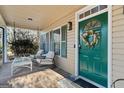 Cozy front porch with rocking chairs, a swing, and a vibrant green door adorned with a floral wreath at 9209 W Banks Mill Rd, Winston, GA 30187
