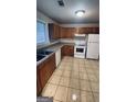 Kitchen featuring wood cabinets, tile floors, and white appliances at 9091 Woodgreen Way, Jonesboro, GA 30238