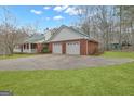 Rear view of red brick house with two car garage, green metal roof, and a spacious well-manicured backyard at 81 Bowers Rd, Moreland, GA 30259