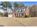 Side view of a brick home with dormer windows, two-car garage and landscaped front yard at 306 Interlake Pass, Mcdonough, GA 30252