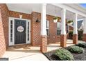 Inviting front porch with brick columns, decorative plants, and a 'Welcome' sign on the front door at 306 Interlake Pass, Mcdonough, GA 30252