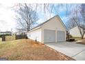 Side view of a two-car garage with a long driveway and fenced yard at 1632 Zacharys Way, Mcdonough, GA 30253